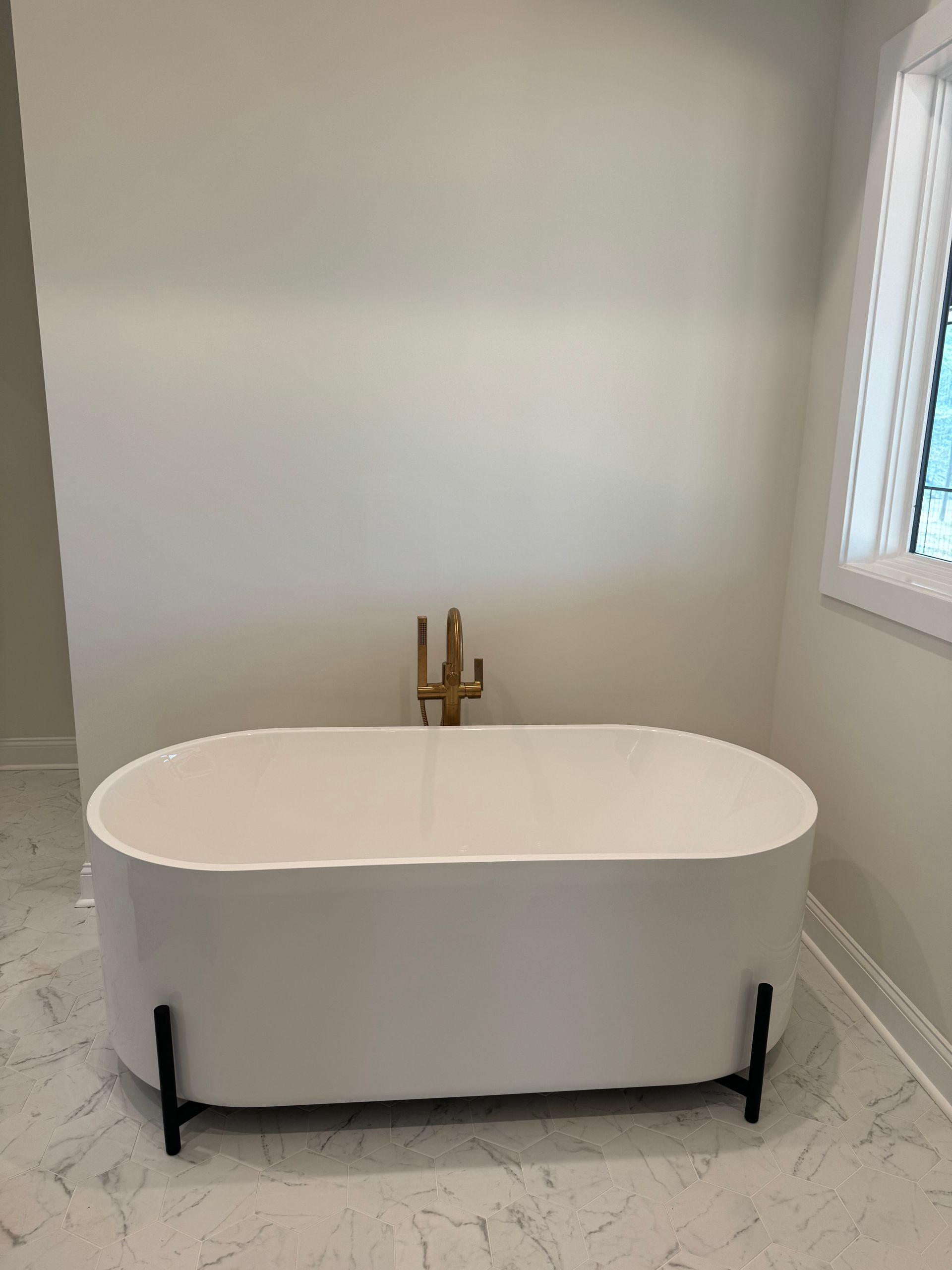 A white bathtub is sitting in a bathroom next to a window.