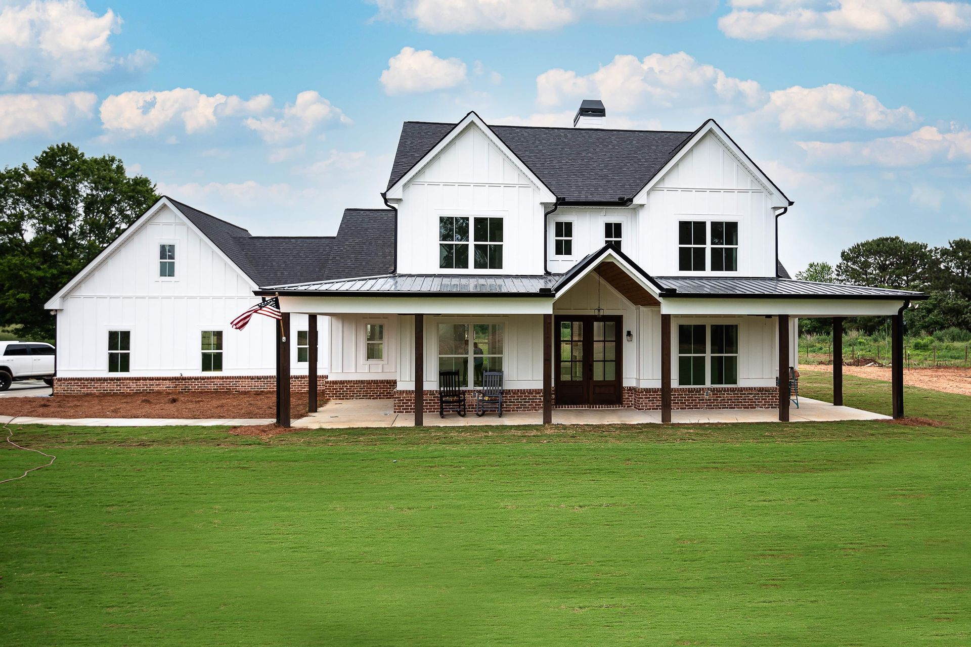A large white house with a porch and a truck parked in front of it.