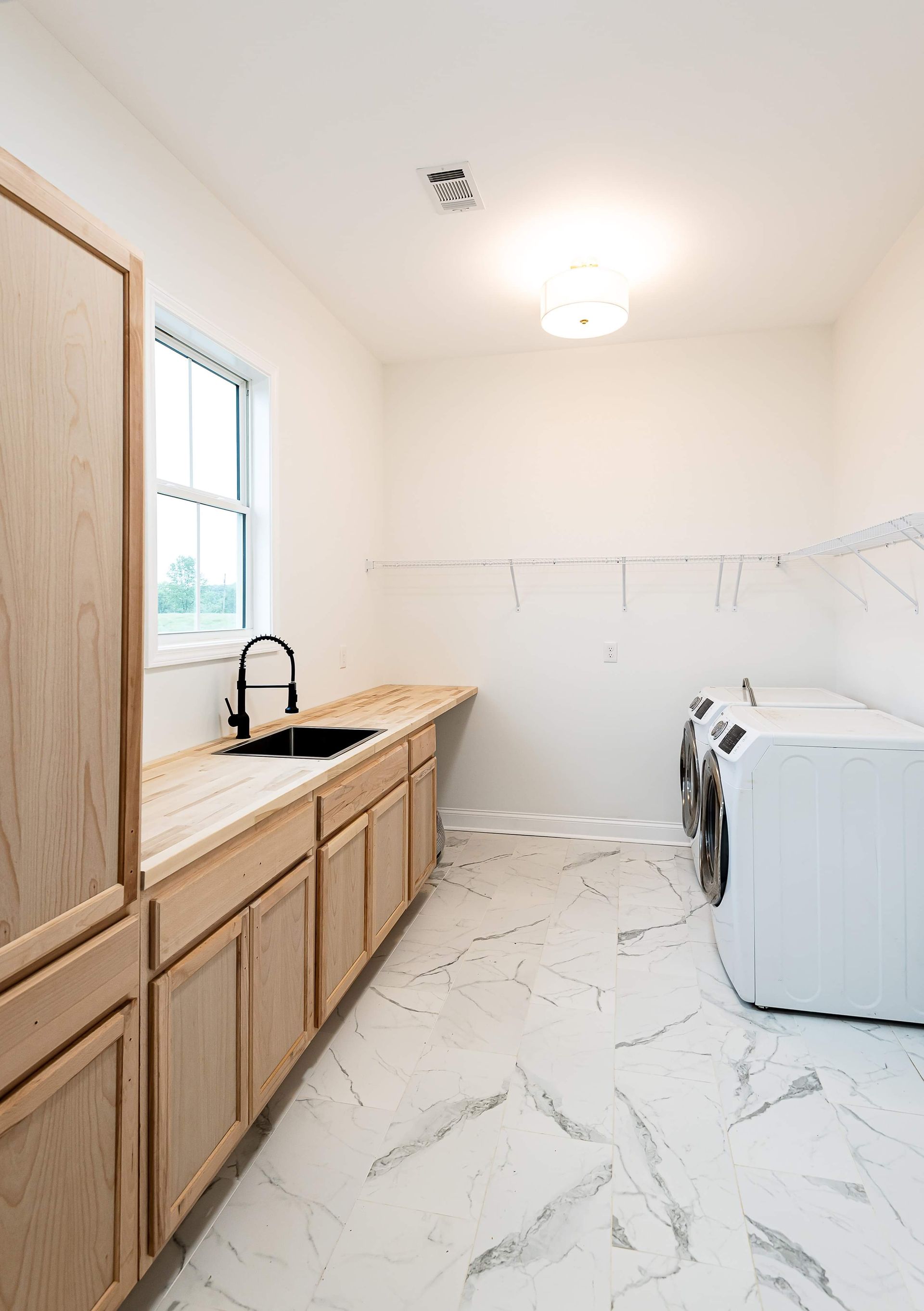 A laundry room with a sink , washer and dryer , and marble floors.