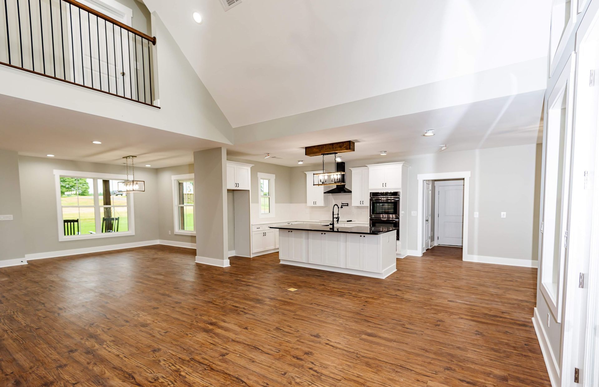 A large empty room with hardwood floors and a kitchen.