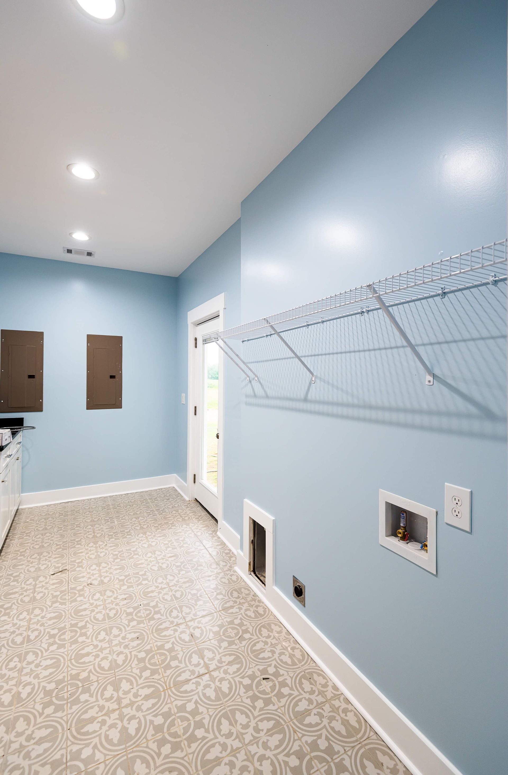 A laundry room with blue walls and a dog door.