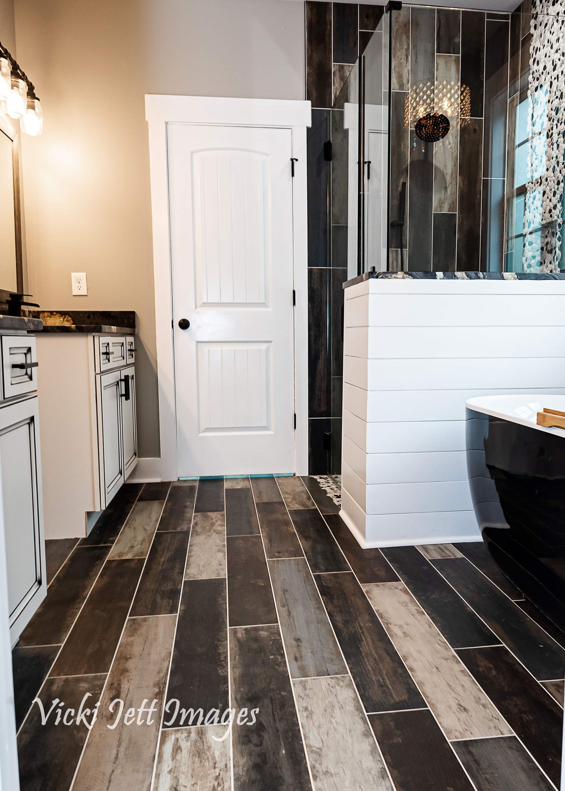 A bathroom with black and white tile floors and a walk in shower.