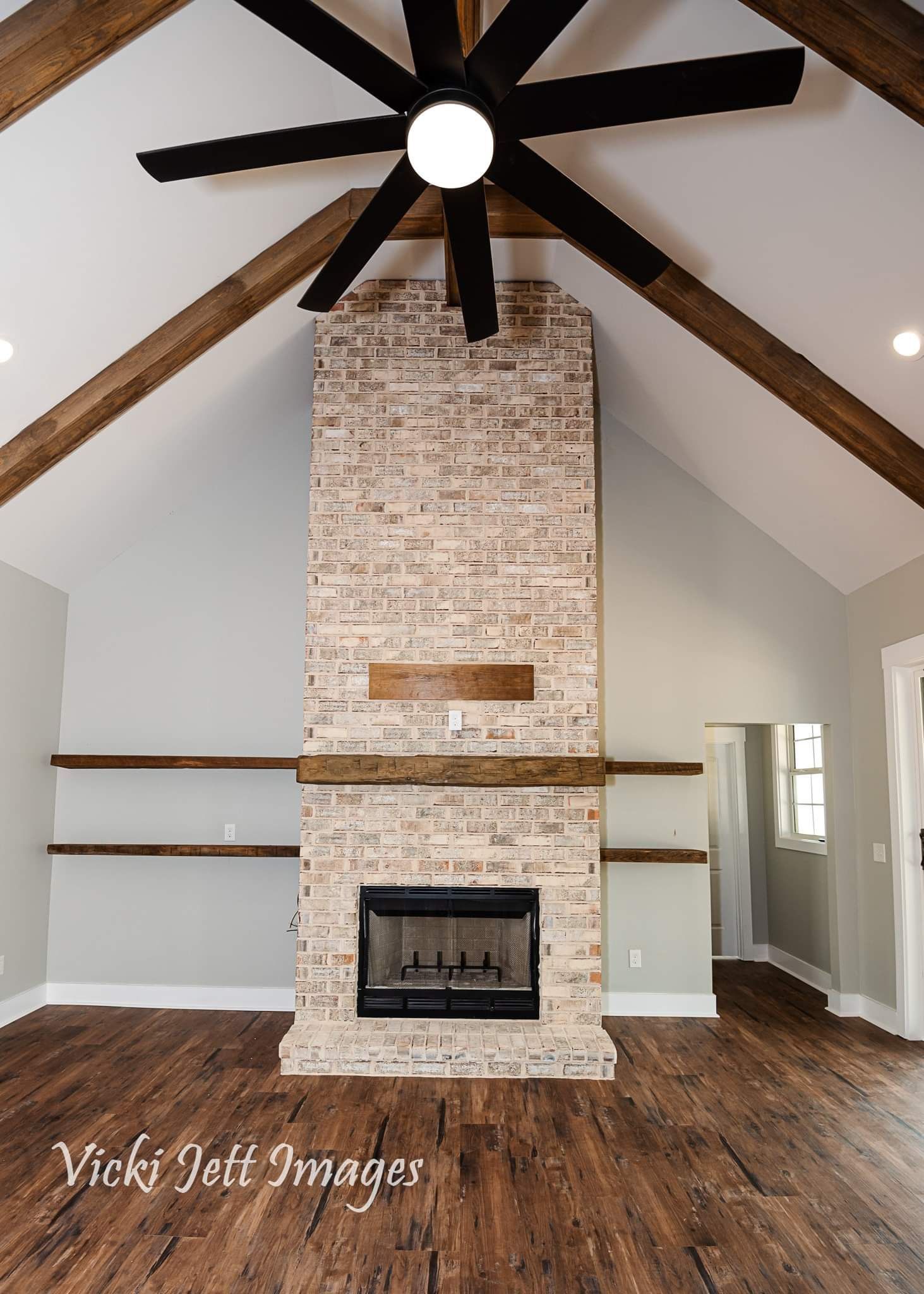 A living room with a fireplace and a ceiling fan.