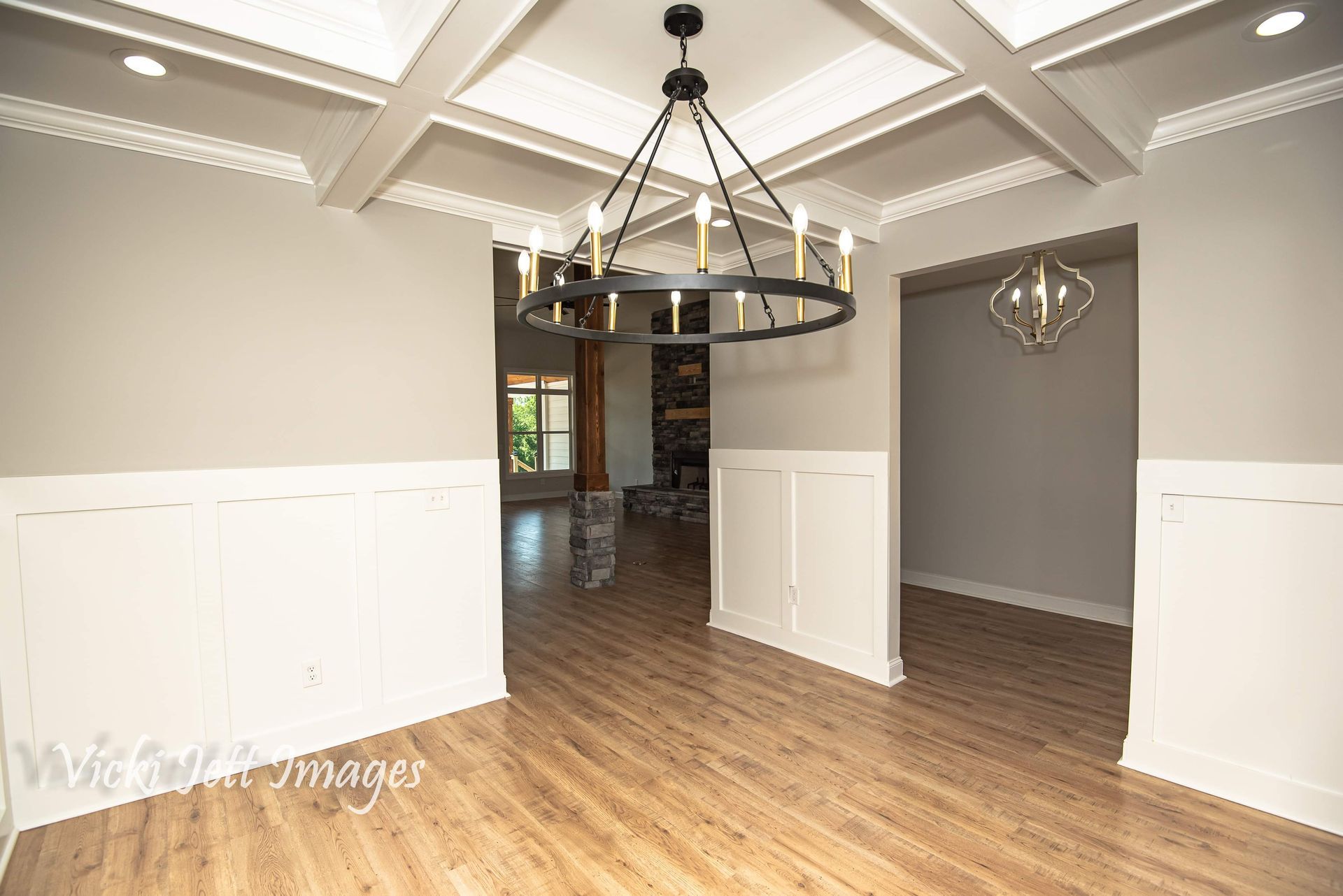 An empty dining room with a chandelier hanging from the ceiling.