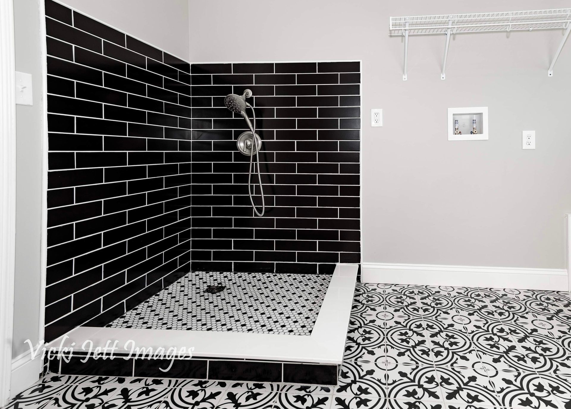 A bathroom with black and white tiles and a walk in shower.