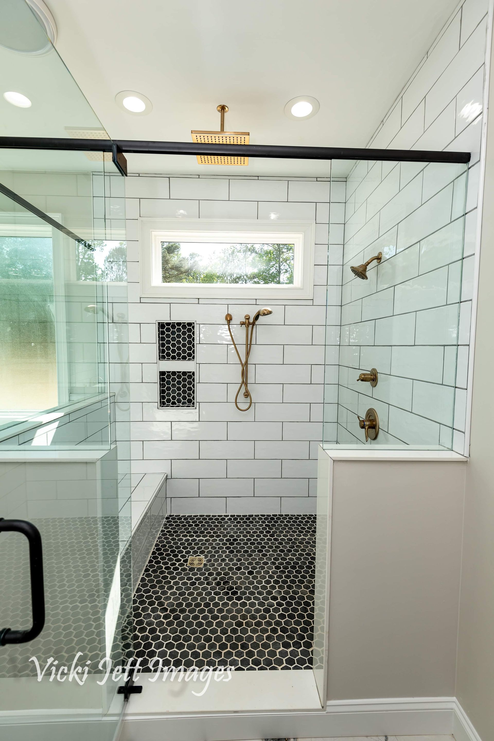 A bathroom with a walk in shower and a window.