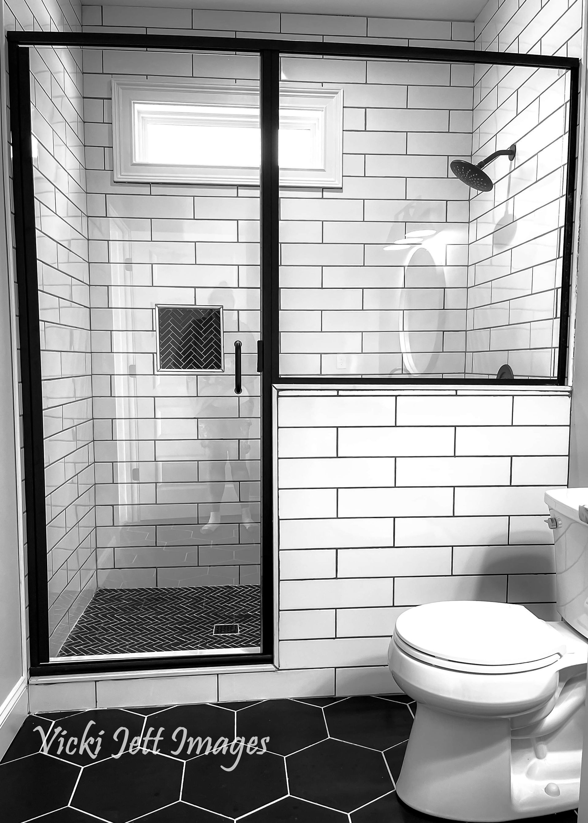 A black and white photo of a bathroom with white brick walls and a toilet.
