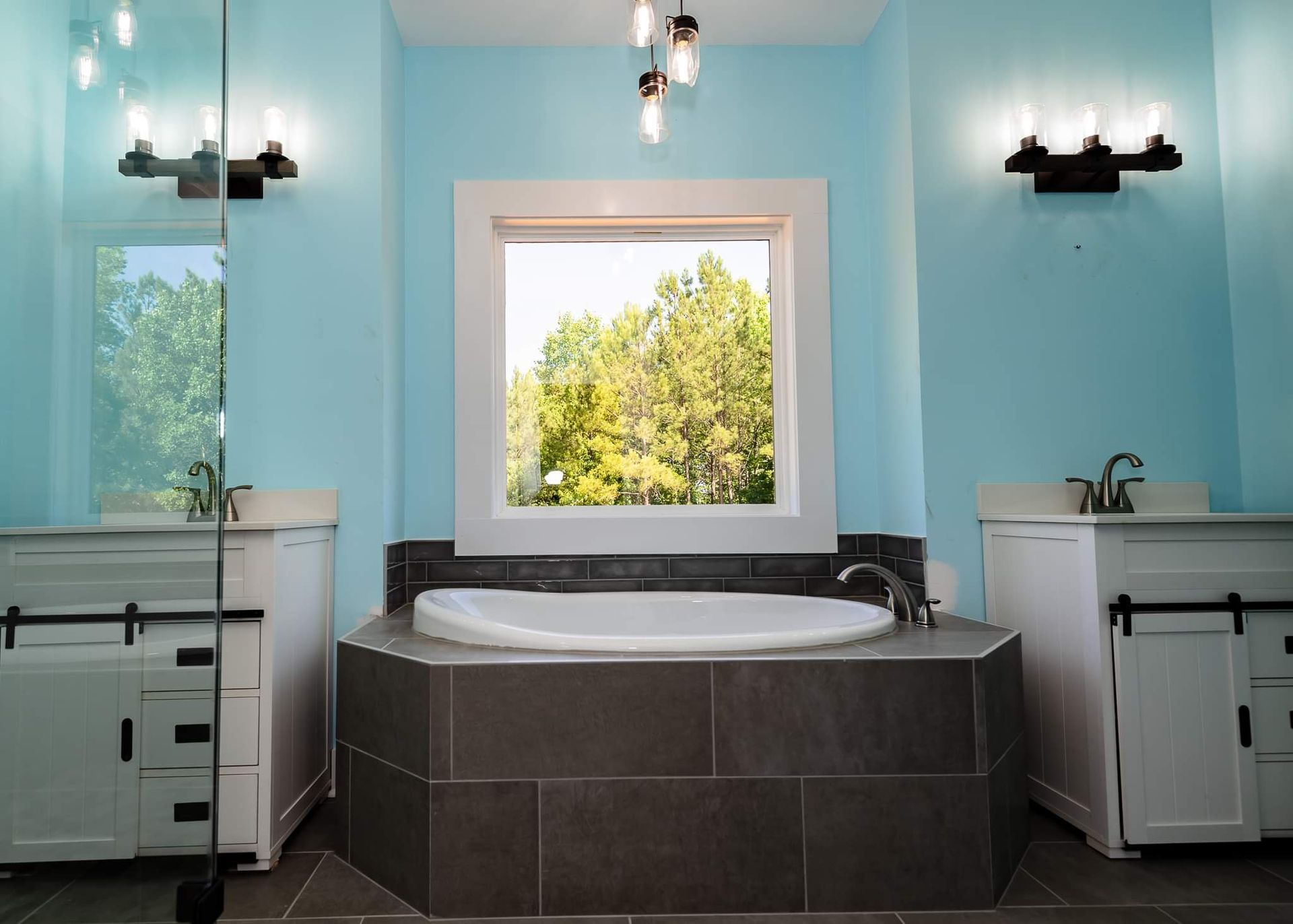 A bathroom with two sinks and a tub with a window