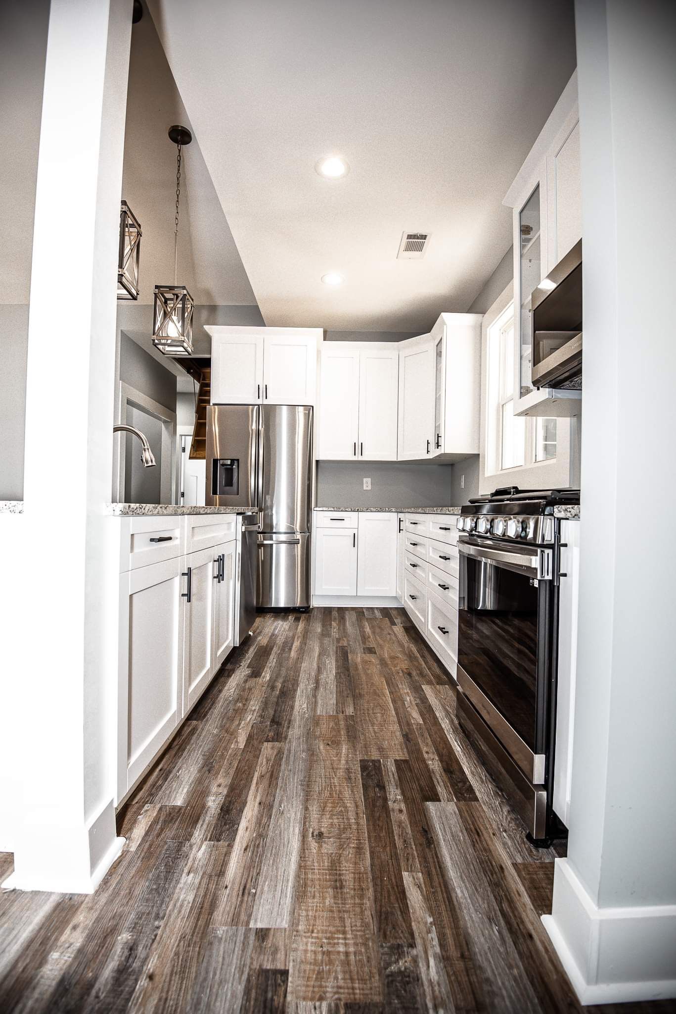 A kitchen with white cabinets , stainless steel appliances , and wooden floors.
