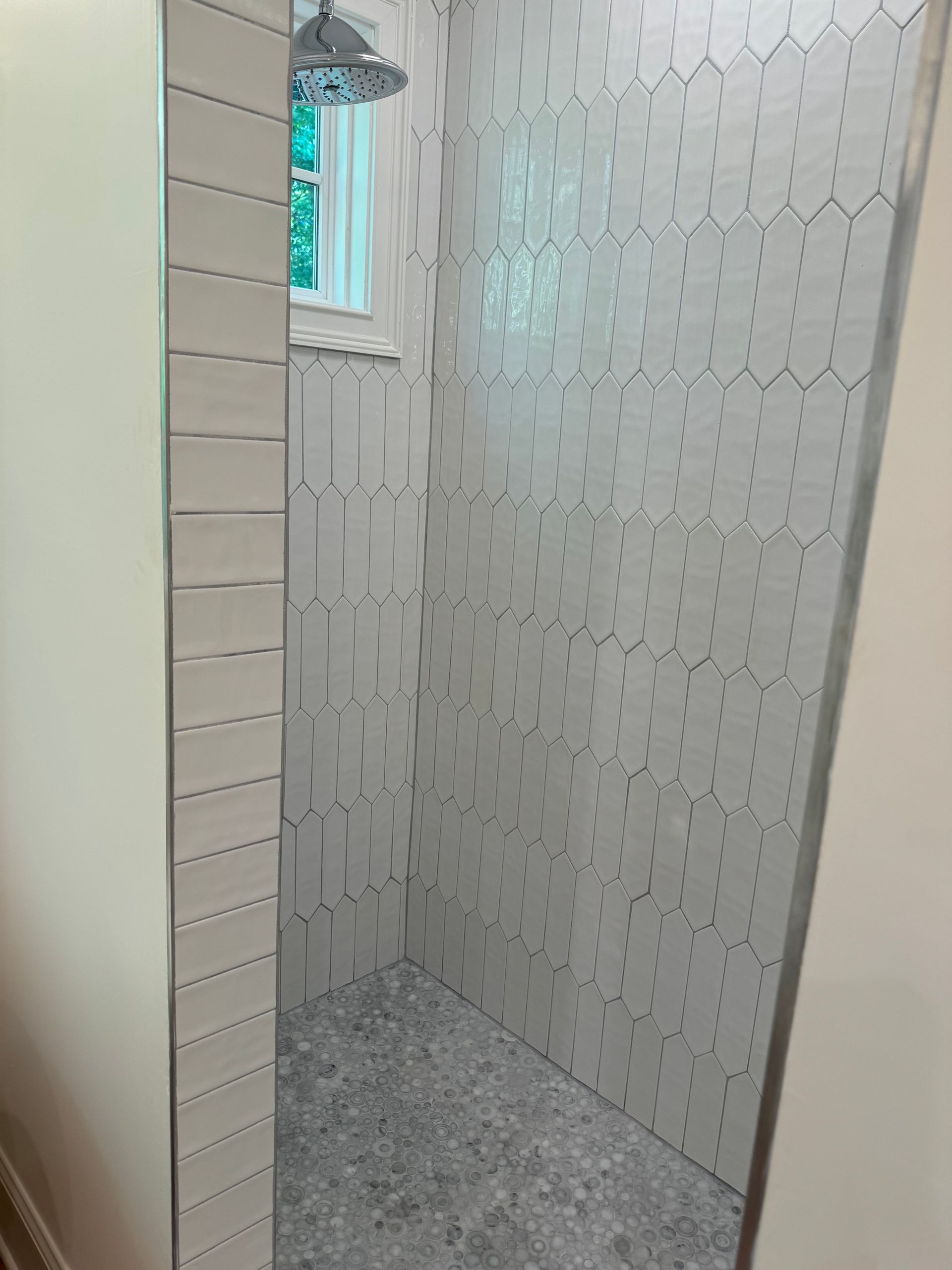 A bathroom with a walk in shower and a window.