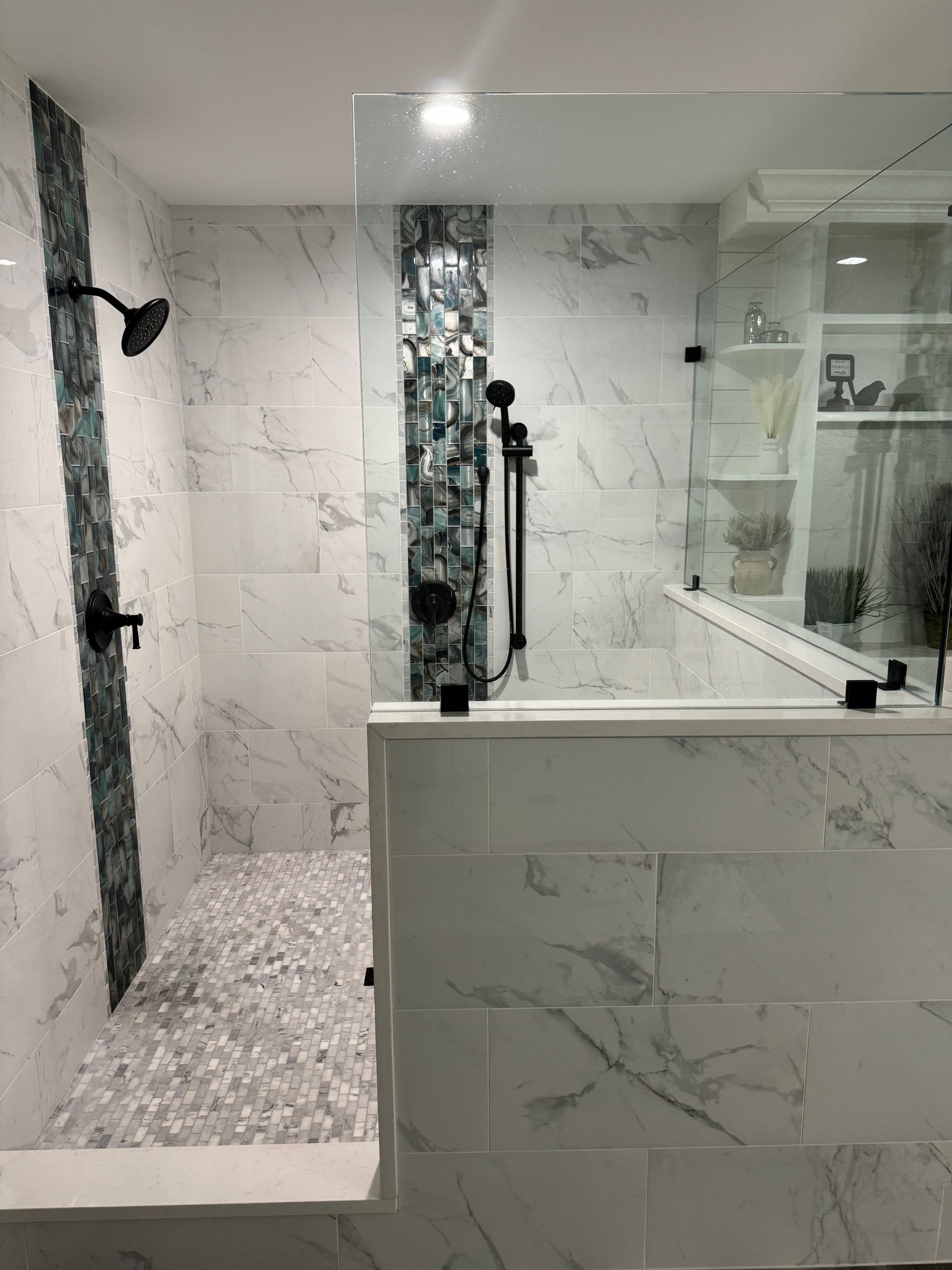 A bathroom with marble tiles and a walk in shower with a glass door.