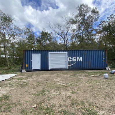 Blue shipping container modified with a door and garage door