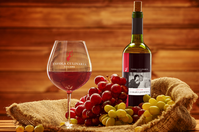 Wine bottle and glass with red wine, grapes, and sackcloth against a wood background.