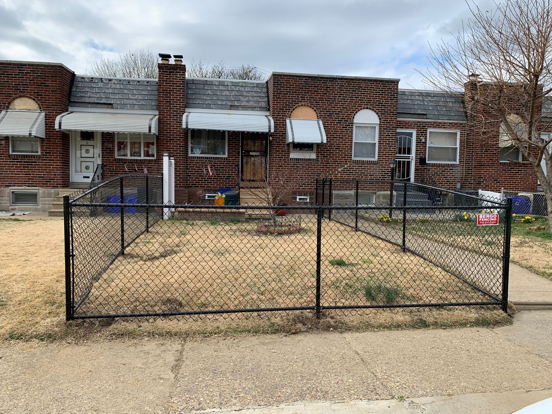 Row houses with chain-link fence in front yards. Brick exteriors, awnings, overcast sky. Row houses with chain-link fence in front yards. Brick exteriors, awnings, overcast sky.