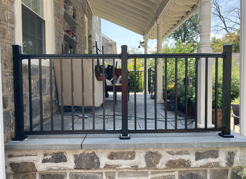 Black chain-link fence on a sloped green lawn with steps leading to a house in a residential setting. Black chain-link fence on a sloped green lawn with steps leading to a house in a residential setting.