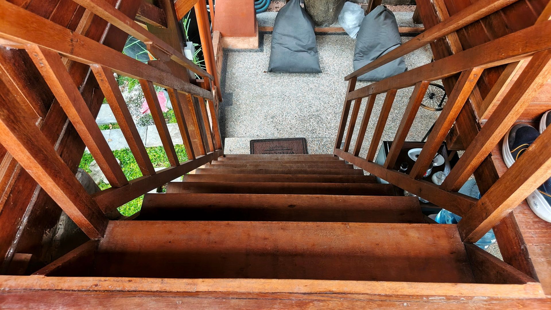 Wooden staircase leading down to a gravel area with seating and partial view of a green lawn. Wooden staircase leading down to a gravel area with seating and partial view of a green lawn.