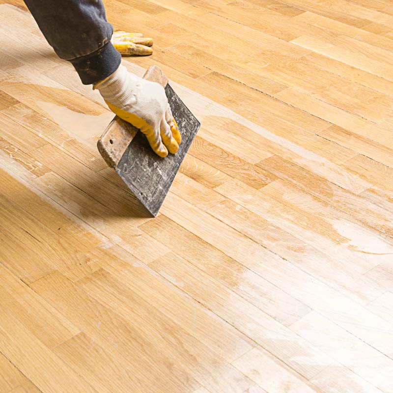 gloved hand polishing wood floor