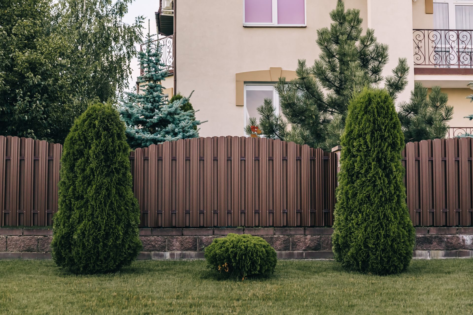 A wooden fence with trees in front of a house.
