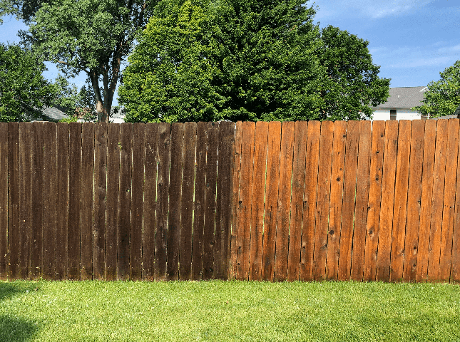 A wooden fence showing a side-by-side comparison of dirty, dark wood and clean, light-colored restored wood.