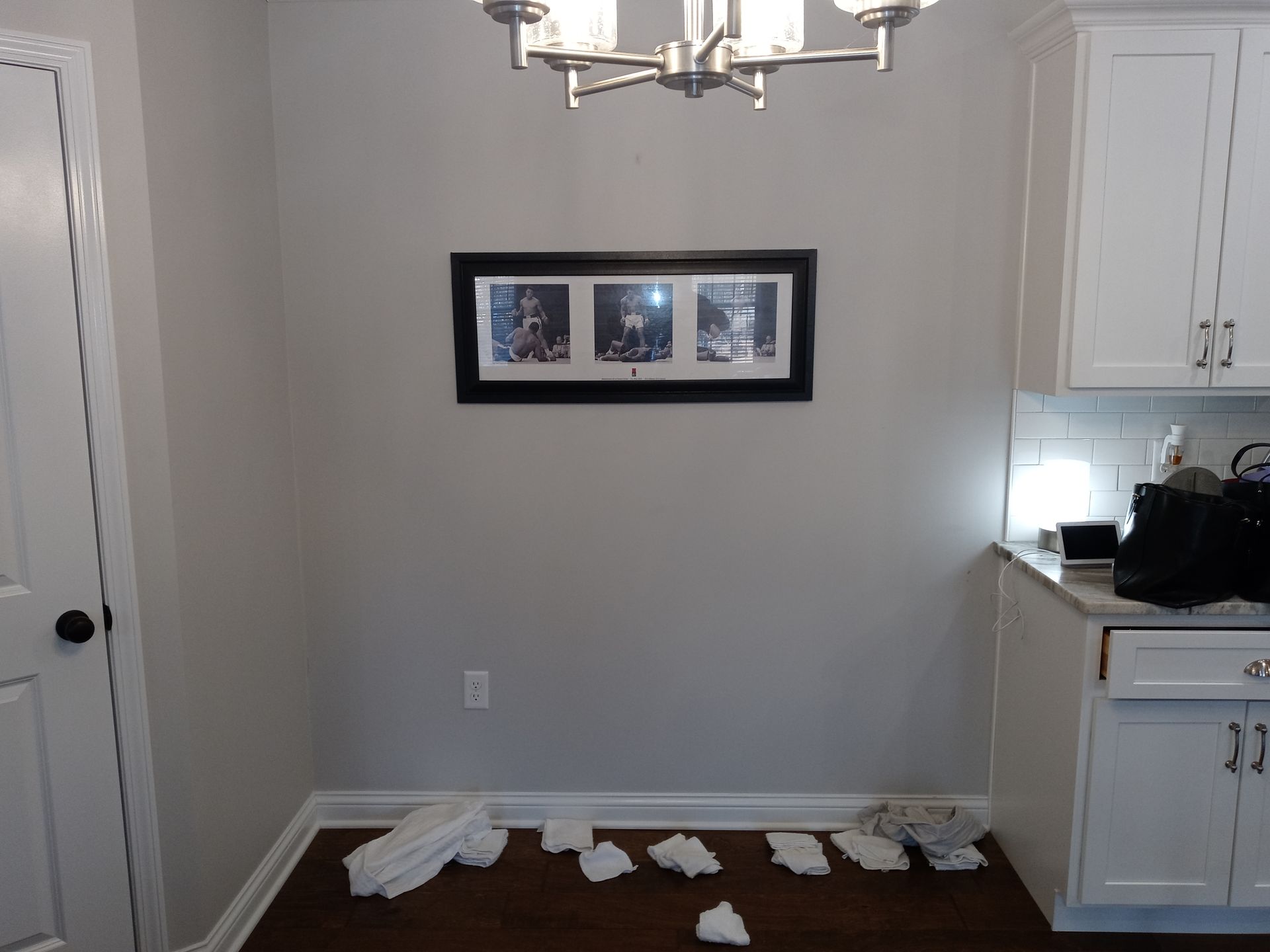 A dining area with light gray walls, a white cabinet, and several crumpled pieces of white paper scattered on the floor.