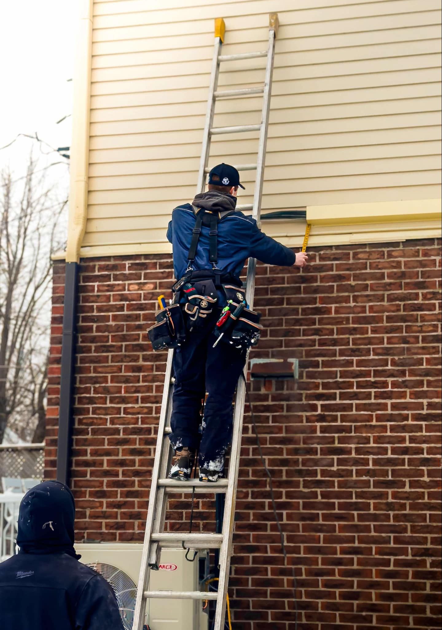 Un homme est debout sur une échelle et peint un mur de briques.