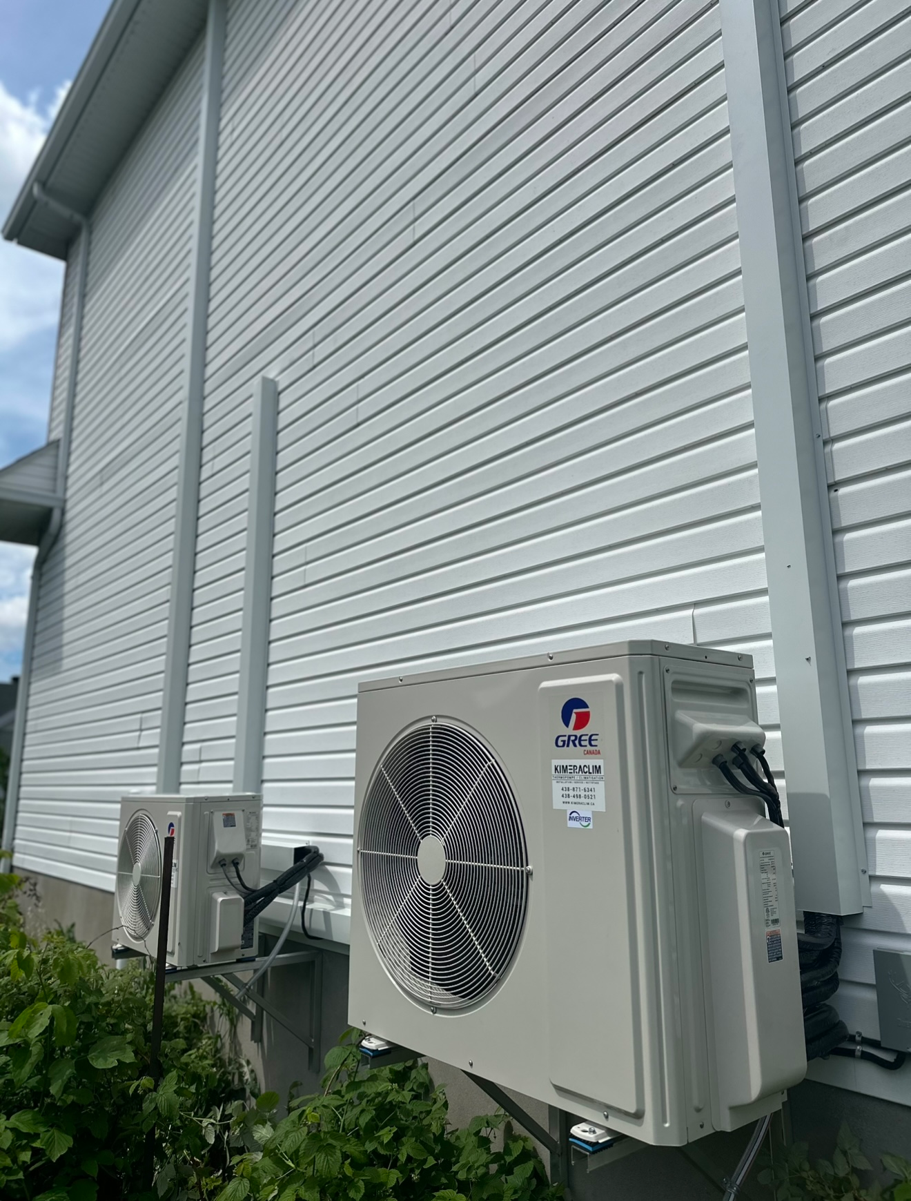 Deux climatiseurs sont installés sur le côté d'une maison.