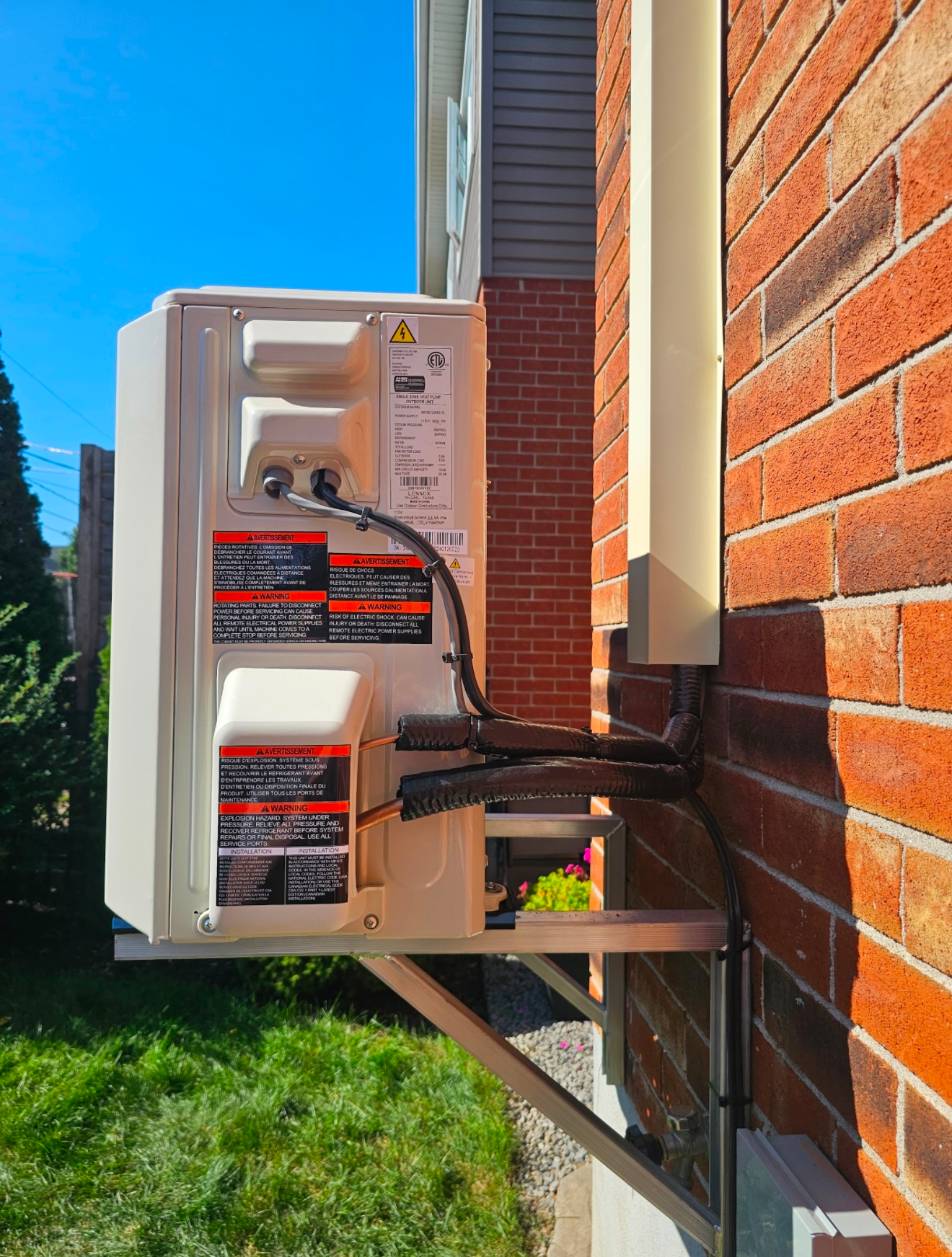 Un climatiseur blanc est monté sur le côté d'un bâtiment en briques.