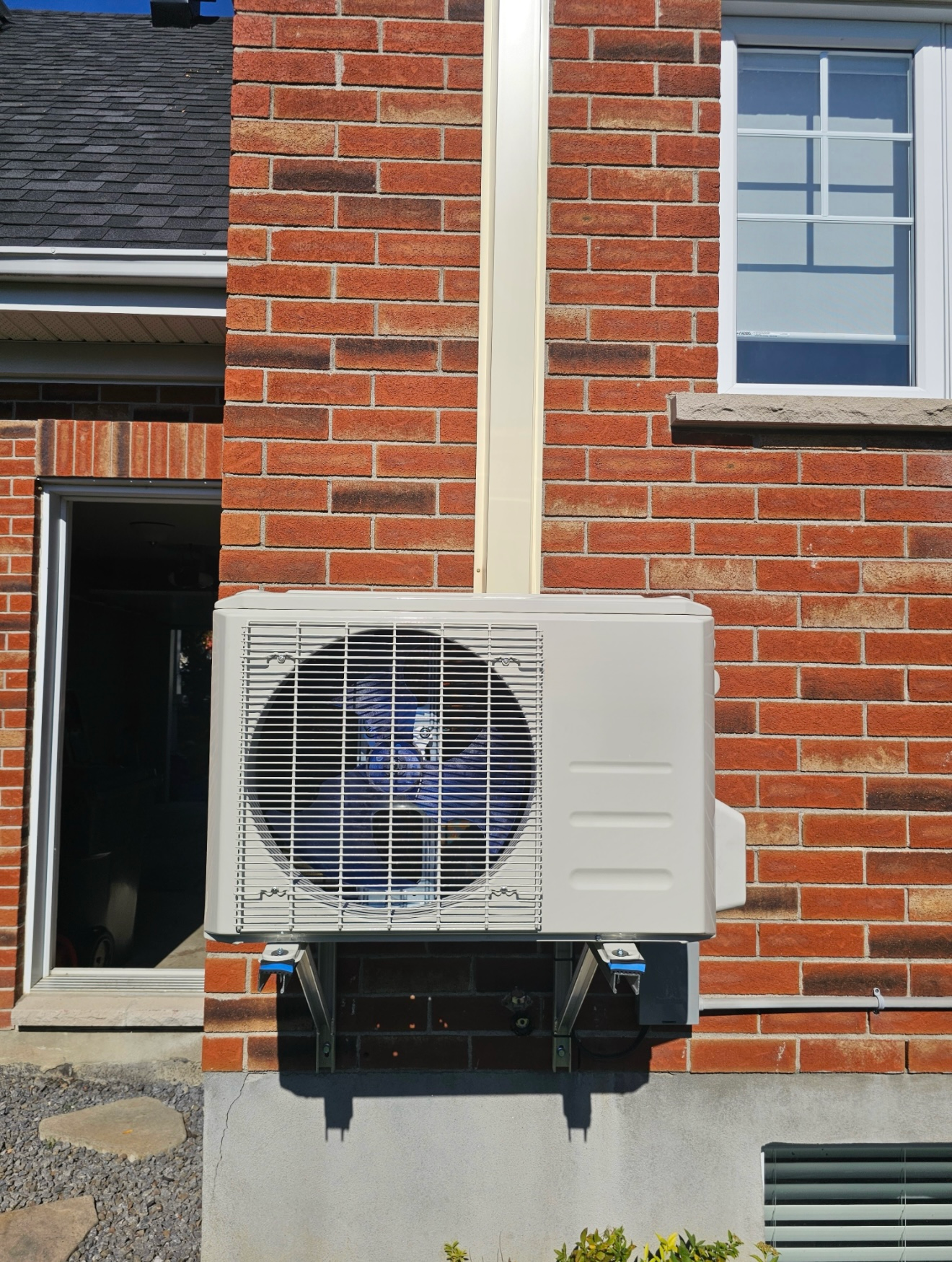 Un climatiseur blanc est monté sur le côté d'un bâtiment en briques