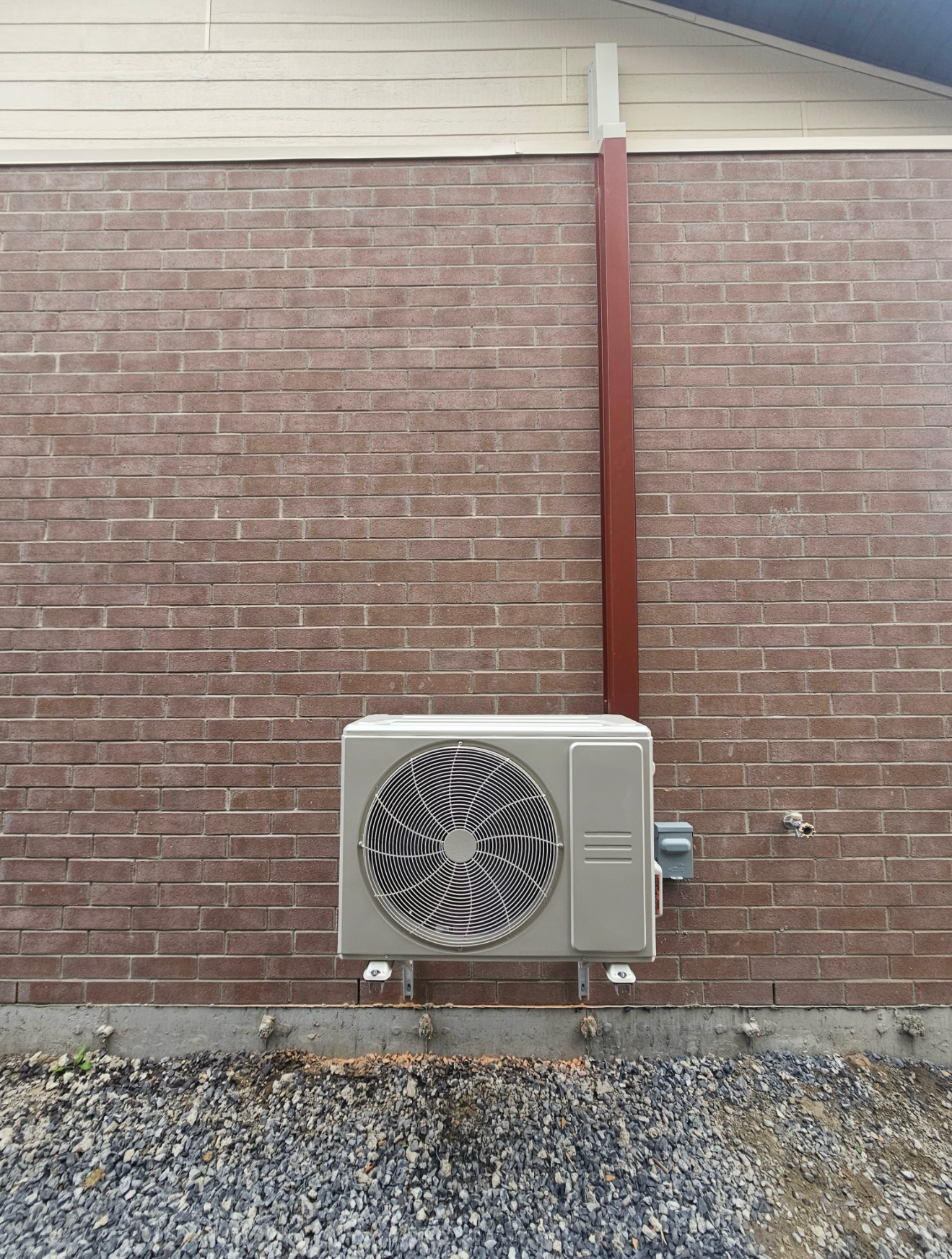 Un climatiseur est monté sur le côté d'un bâtiment en briques.