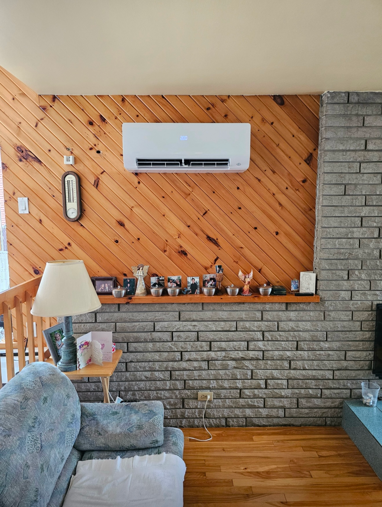 Un salon avec une cheminée en brique, un canapé, une lampe et un climatiseur.