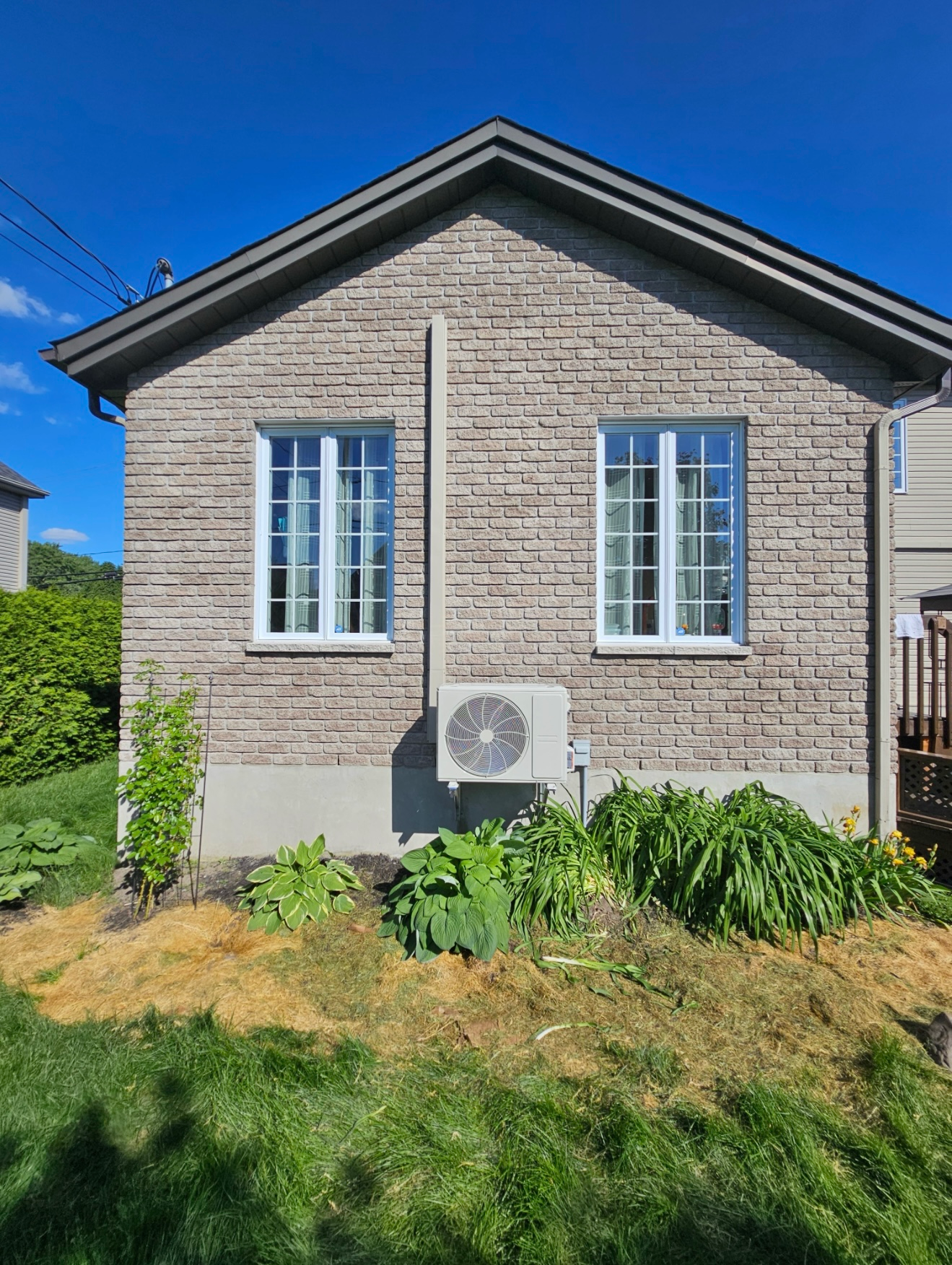 Une petite maison en briques avec deux fenêtres et un climatiseur sur le côté.