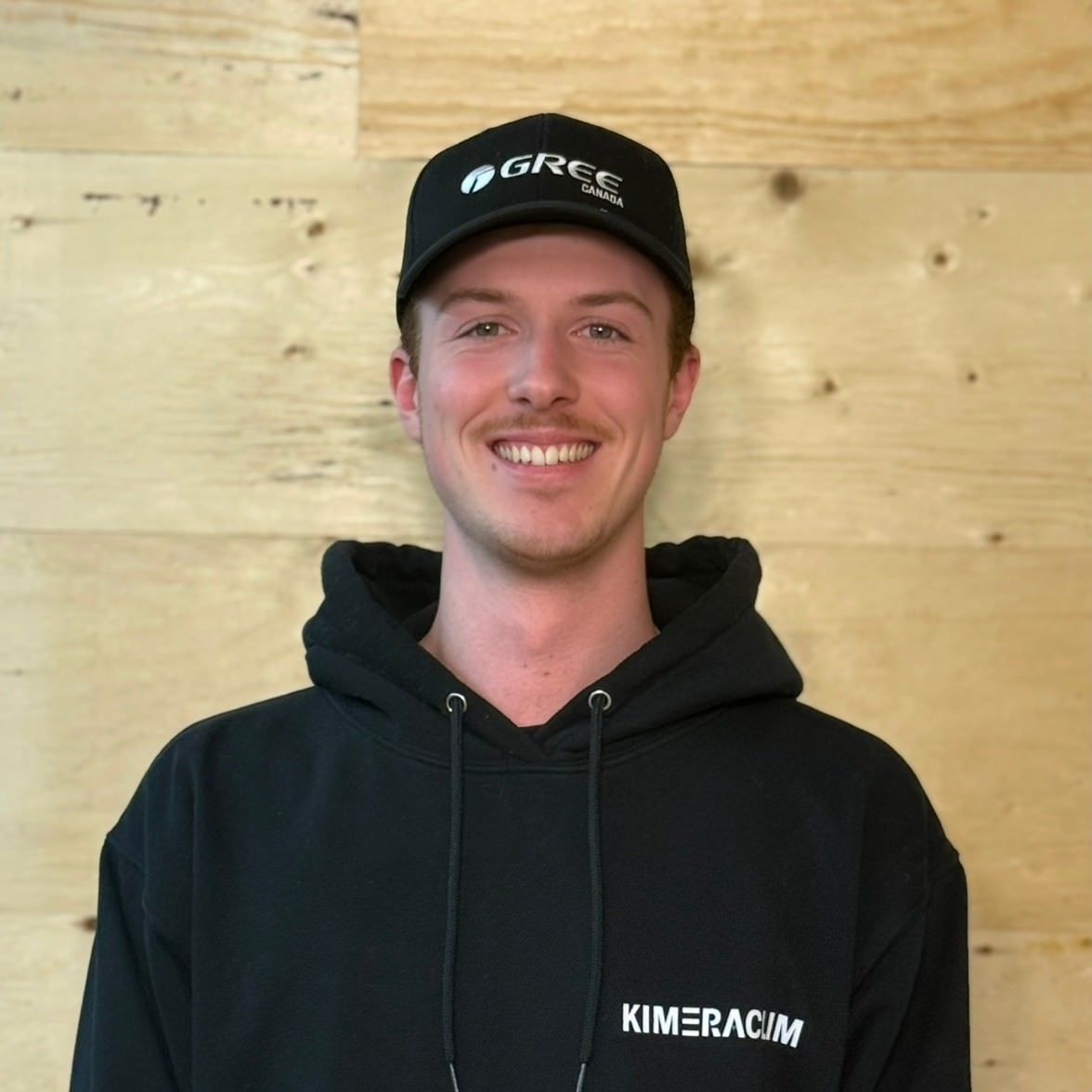 Un homme portant un sweat à capuche noir et un chapeau noir avec Greg dessus