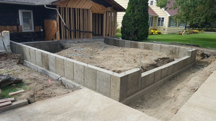 Concrete foundation walls for a new house addition under construction in a residential backyard.