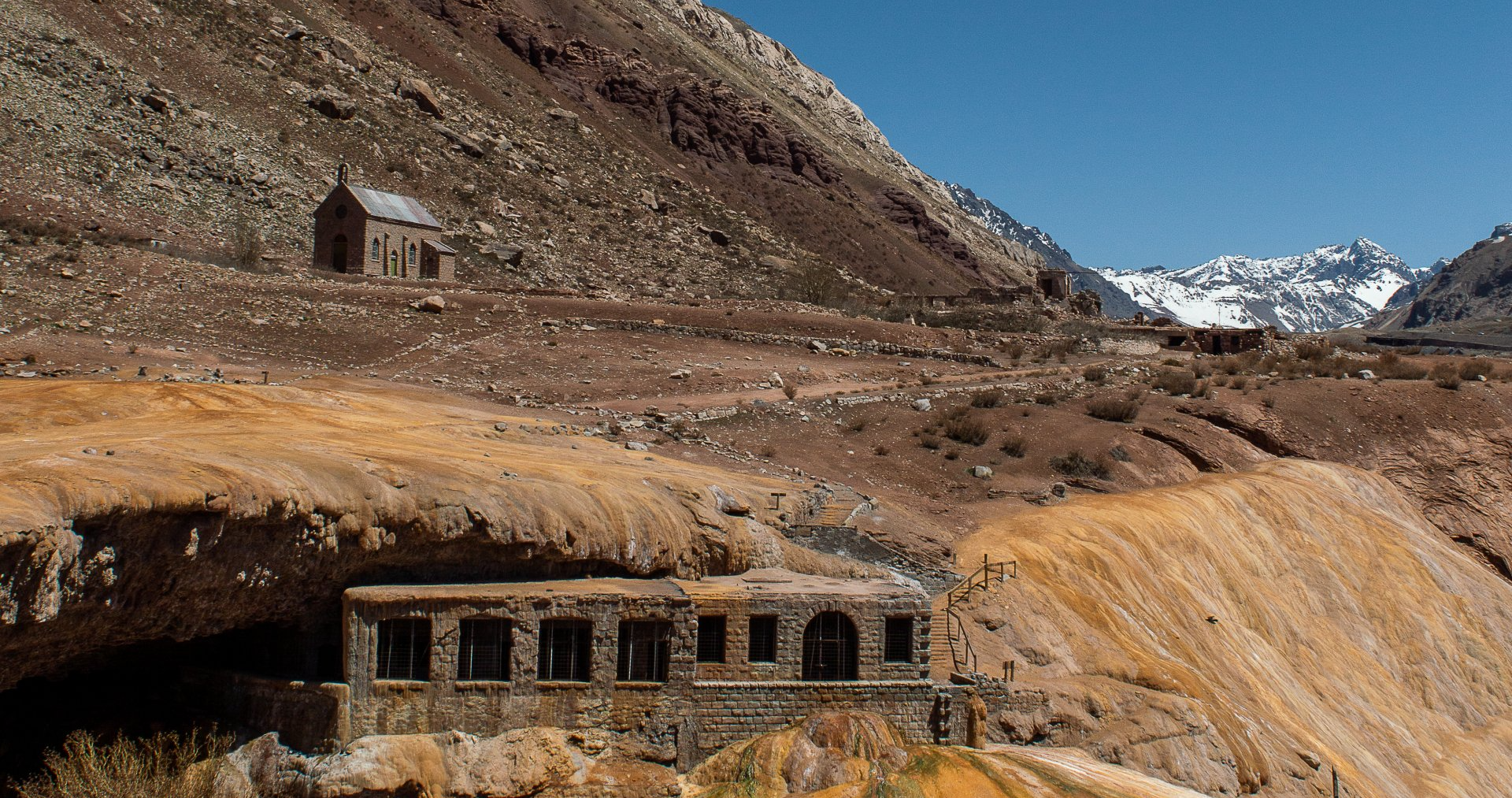 Un edificio en medio de un desierto con montañas al fondo.
