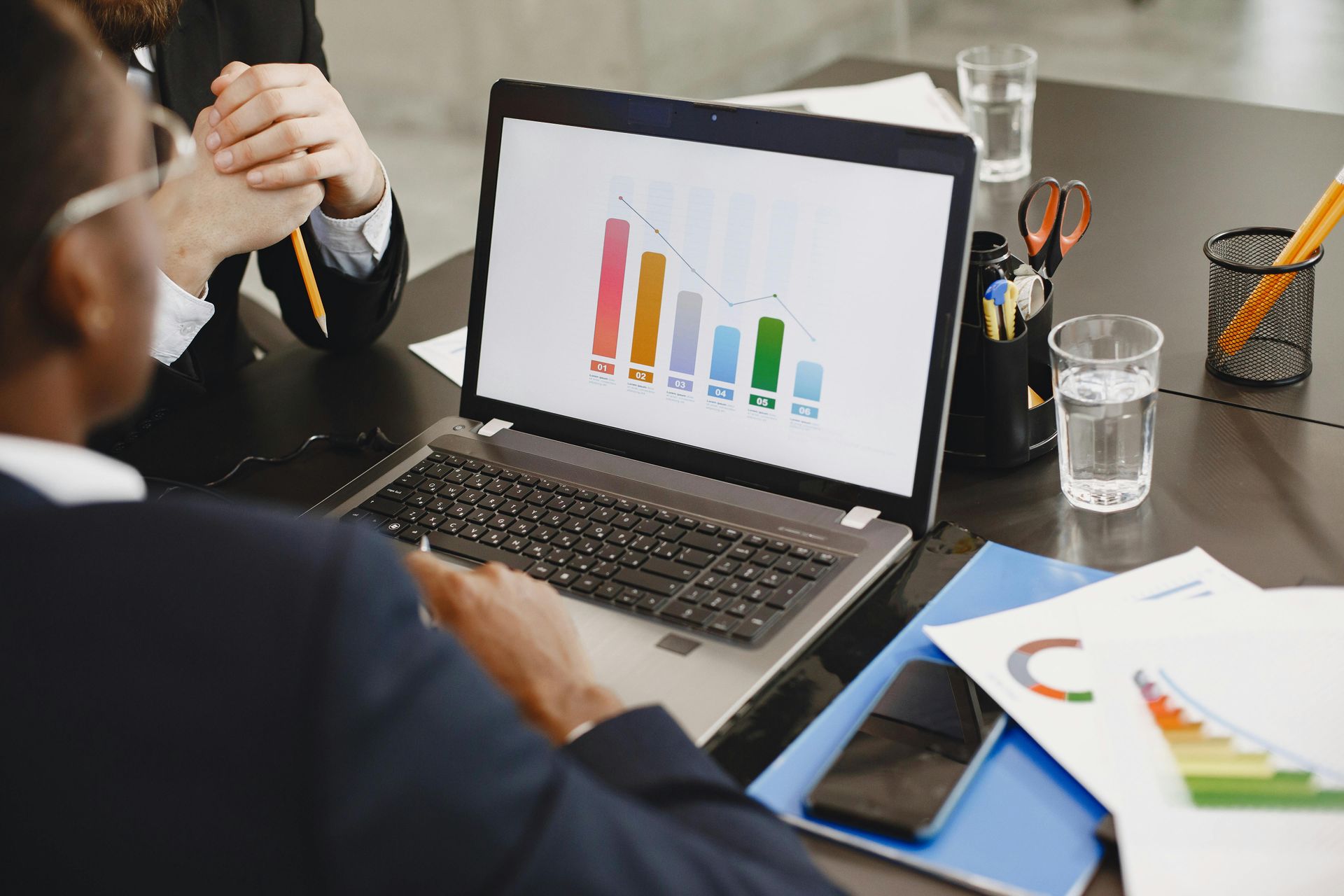 People reviewing colorful charts on a laptop in a meeting room