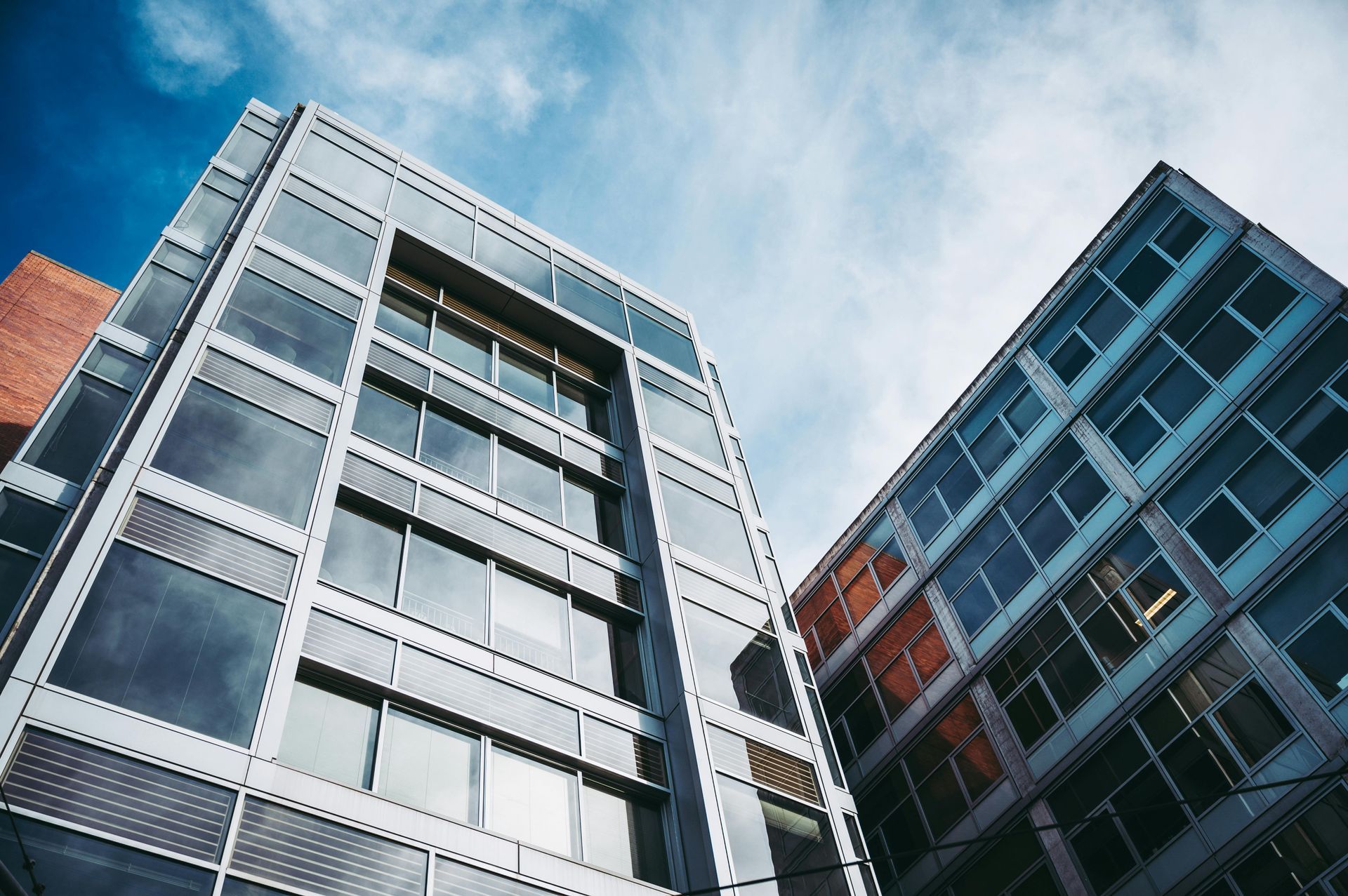 Modern glass office buildings viewed from below against a blue sky