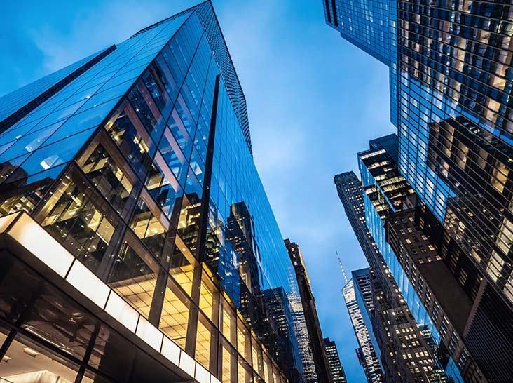 Skyscrapers with reflective glass facades seen from below against a blue sky