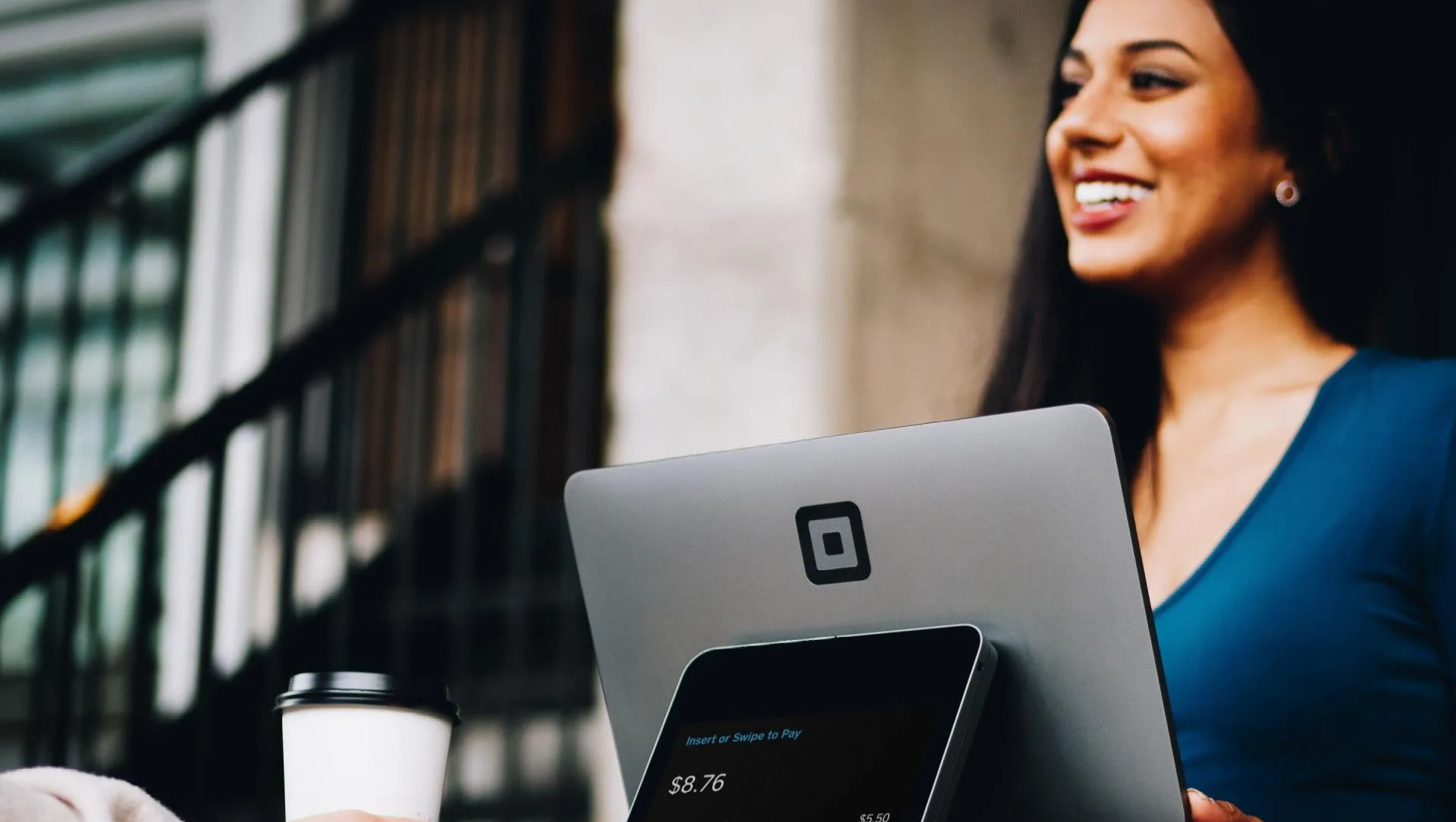 Photo of woman smiling at customer while using tablet to take transaction.
