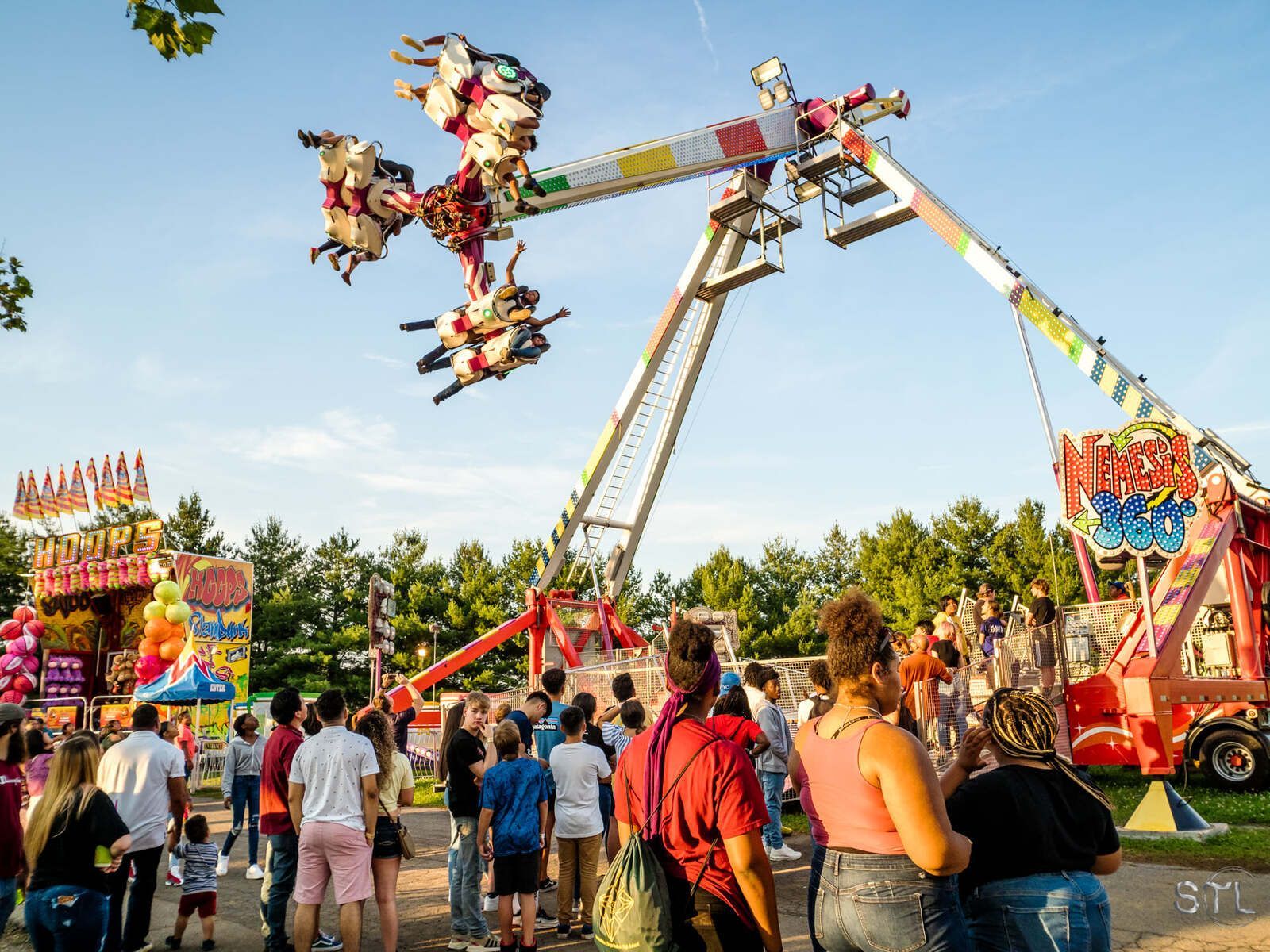 A group of people are standing around a carnival ride.
