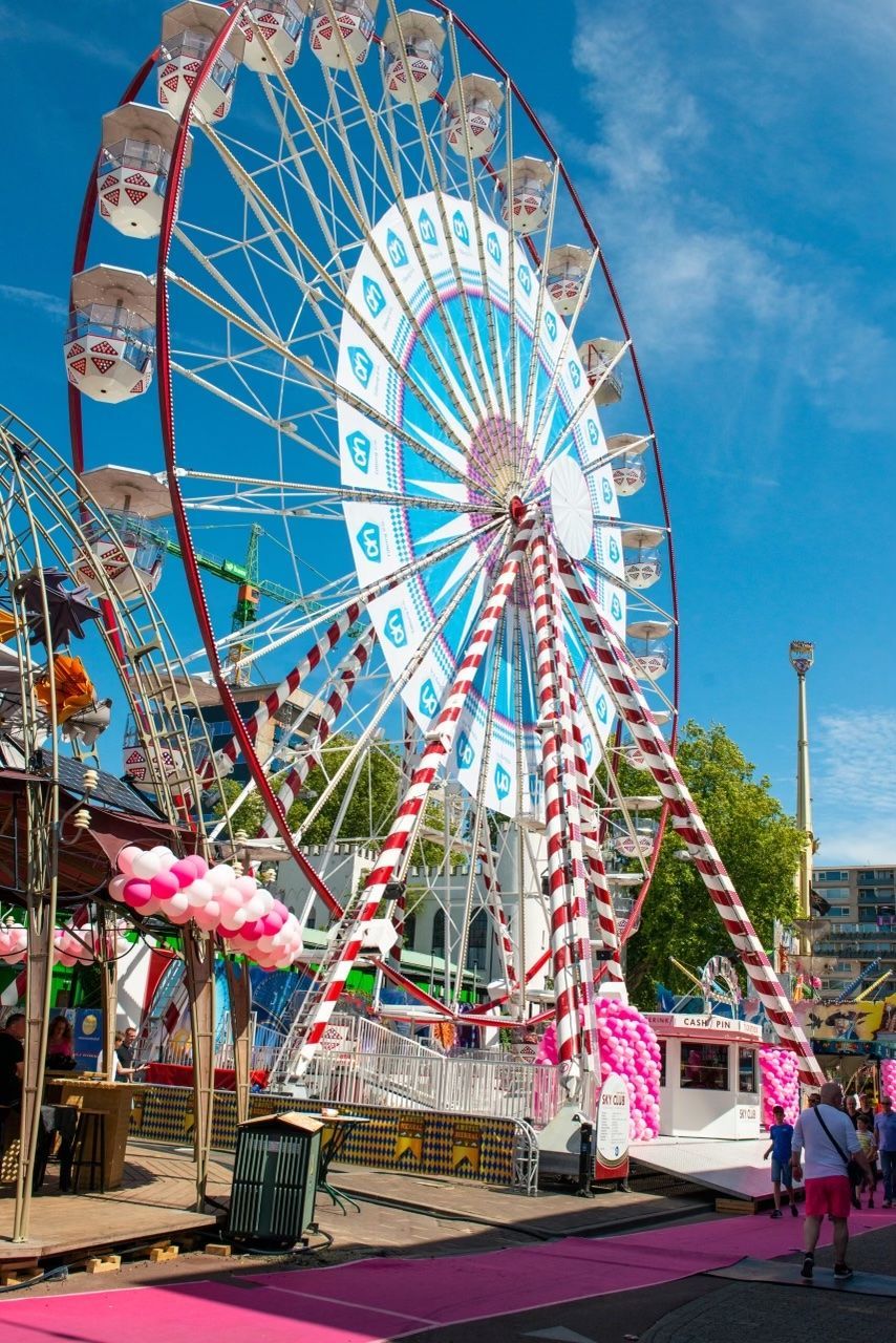 A ferris wheel is decorated with pink balloons at a carnival.