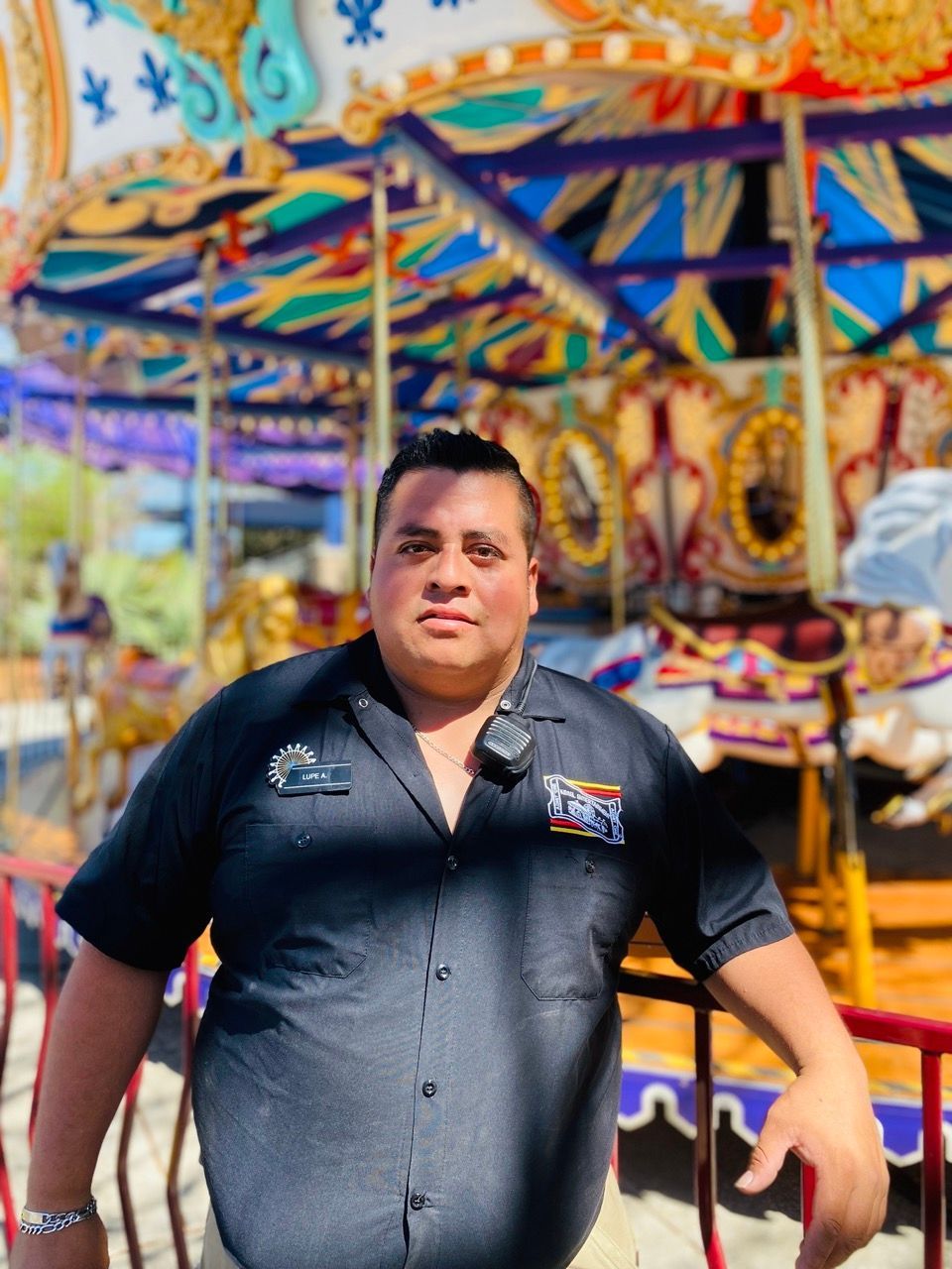 A man in a black shirt is standing in front of a carousel