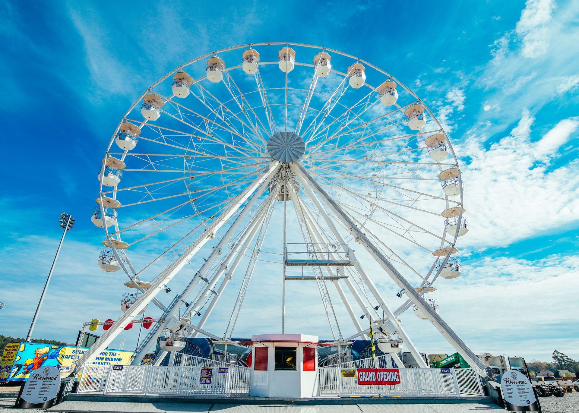 A large ferris wheel is sitting in front of a blue sky.