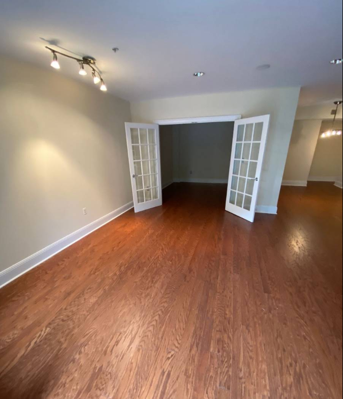 Room with hardwood floors, light walls, and French doors leading to another room.