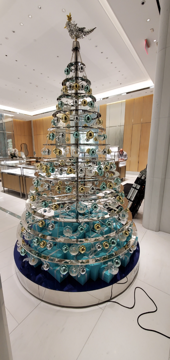 Decorative tree made of glass orbs in a high-end store. Bird topper. Blue, silver, and gold.