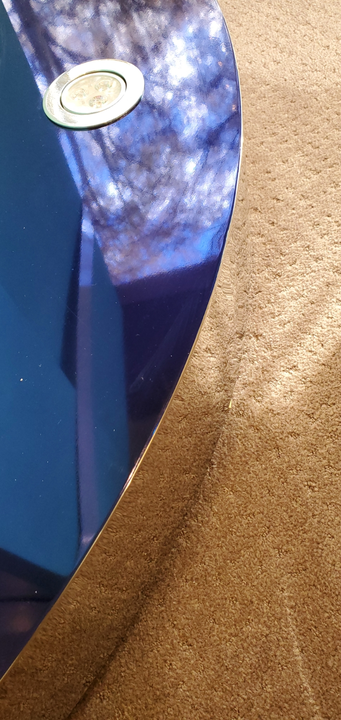 Brown leather curves over a blue surface, a small, silver circular object on the blue.