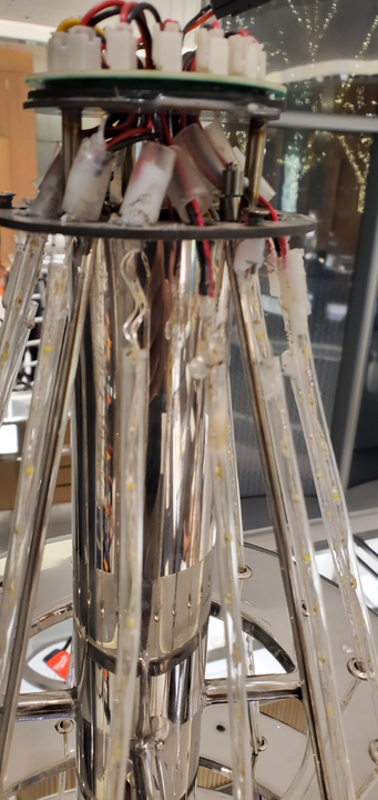 Close-up of a silver, cylindrical structure with embedded lights and electronic components at the top.