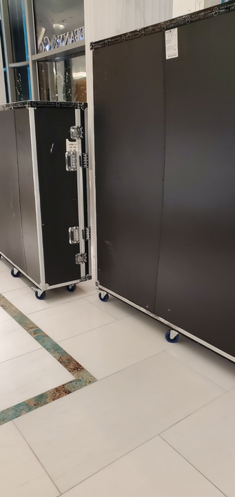 Two black storage cases on wheels in a room with a patterned floor.