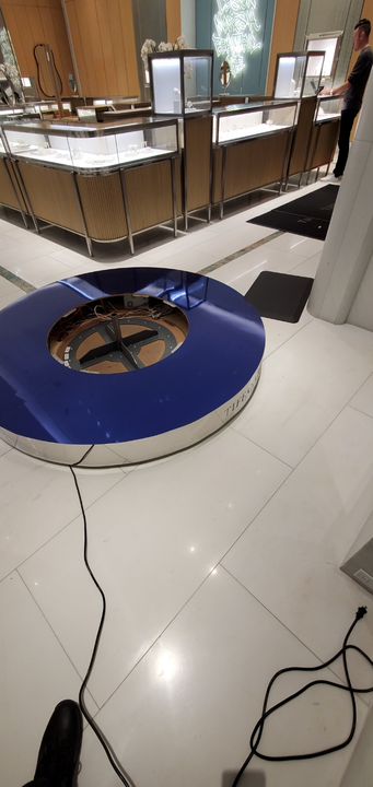 A large, blue and silver circular object on a tiled floor inside a store with displays.