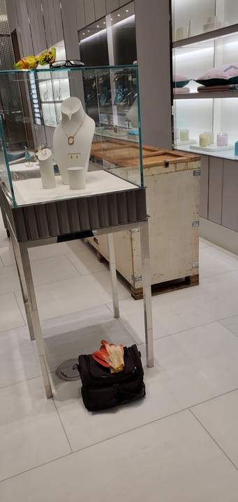 Jewelry display case in a store with jewelry on display, a black bag on the floor.