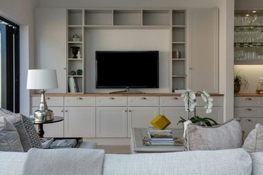 Living room with built-in cabinetry, TV, and couch, in neutral colors.